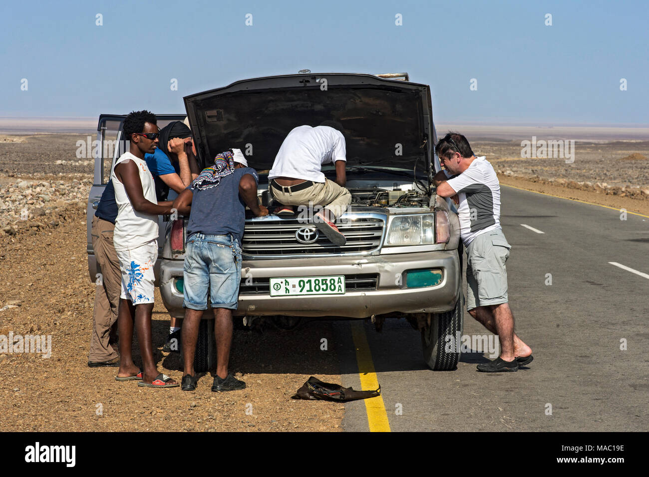 Locals and tourists assisting a car repair on the road in the Danakil depression, Afar Province, Ethiopia Stock Photo