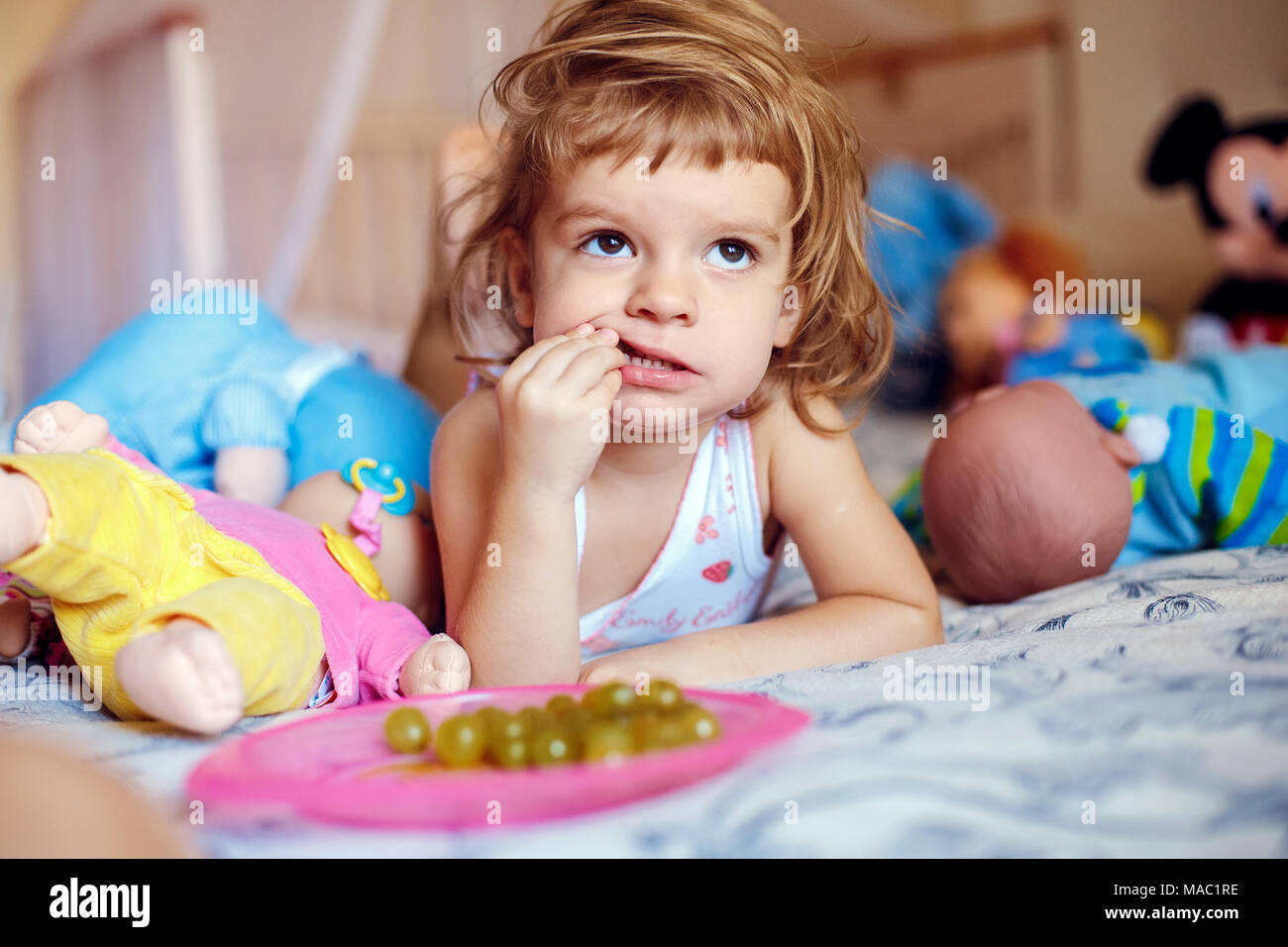Little girl eating grapes on bed Stock Photo Alamy