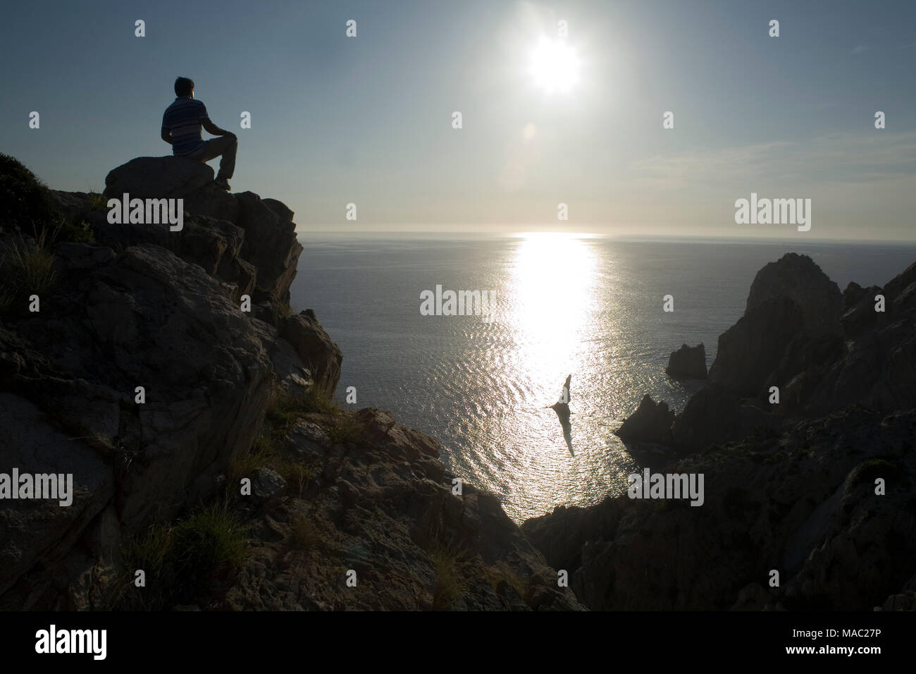 man sitting on a high rock watching the sunrise Stock Photo - Alamy
