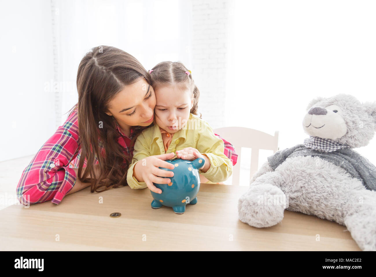 Mother and her child daughter putting coin to piggy bank Stock Photo ...