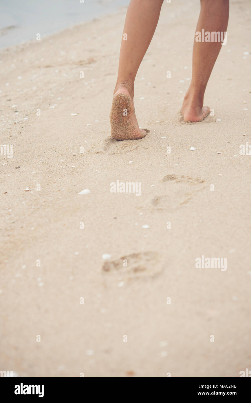 Young woman walking on sand beach leaving footprints in the sand. Beach ...