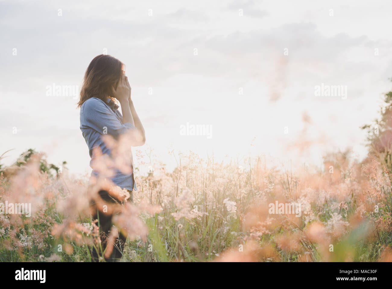 Sad woman standing in field with sunset background Stock Photo - Alamy