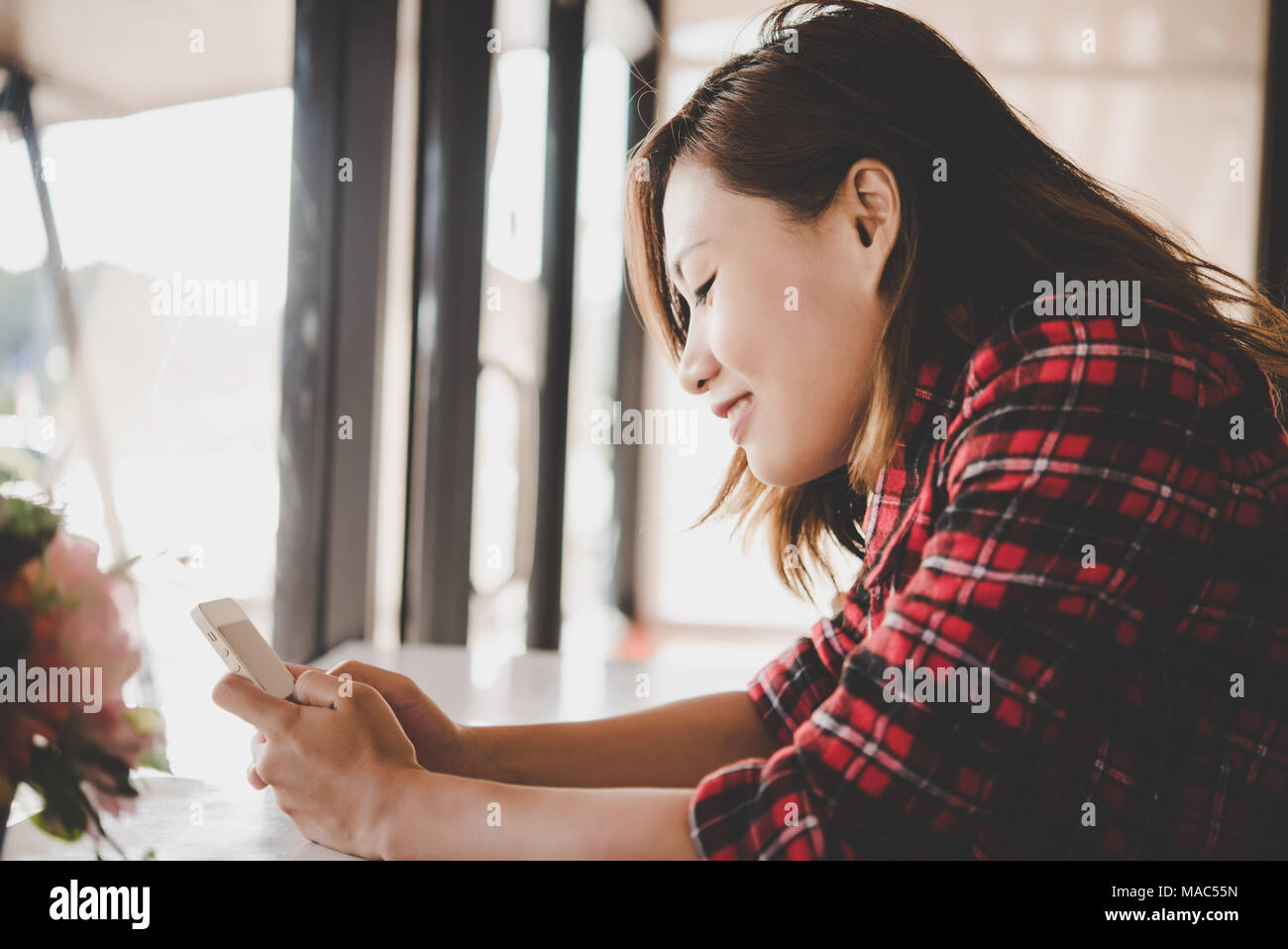 Close up of woman smiling while holding cell phone and texing. Stock Photo
