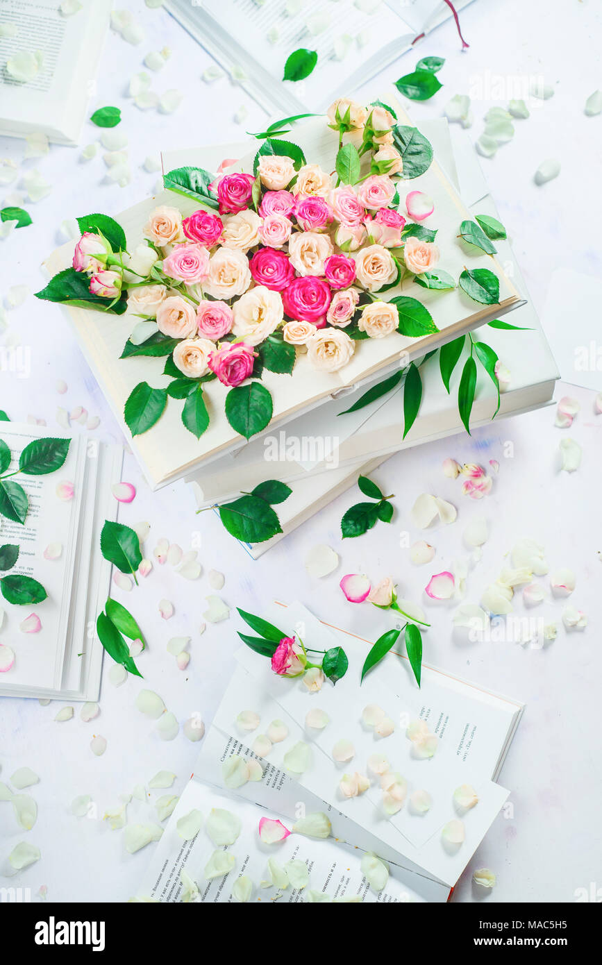 Stack of white books with flowers and petals. Spring reading concept. Feminine still life in high key with copy space. Stock Photo