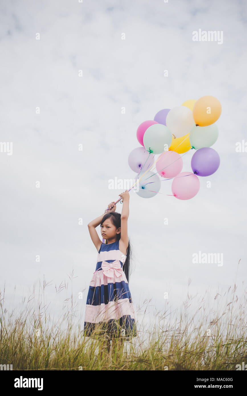Little girl playing with balloons on meadows field Stock Photo - Alamy