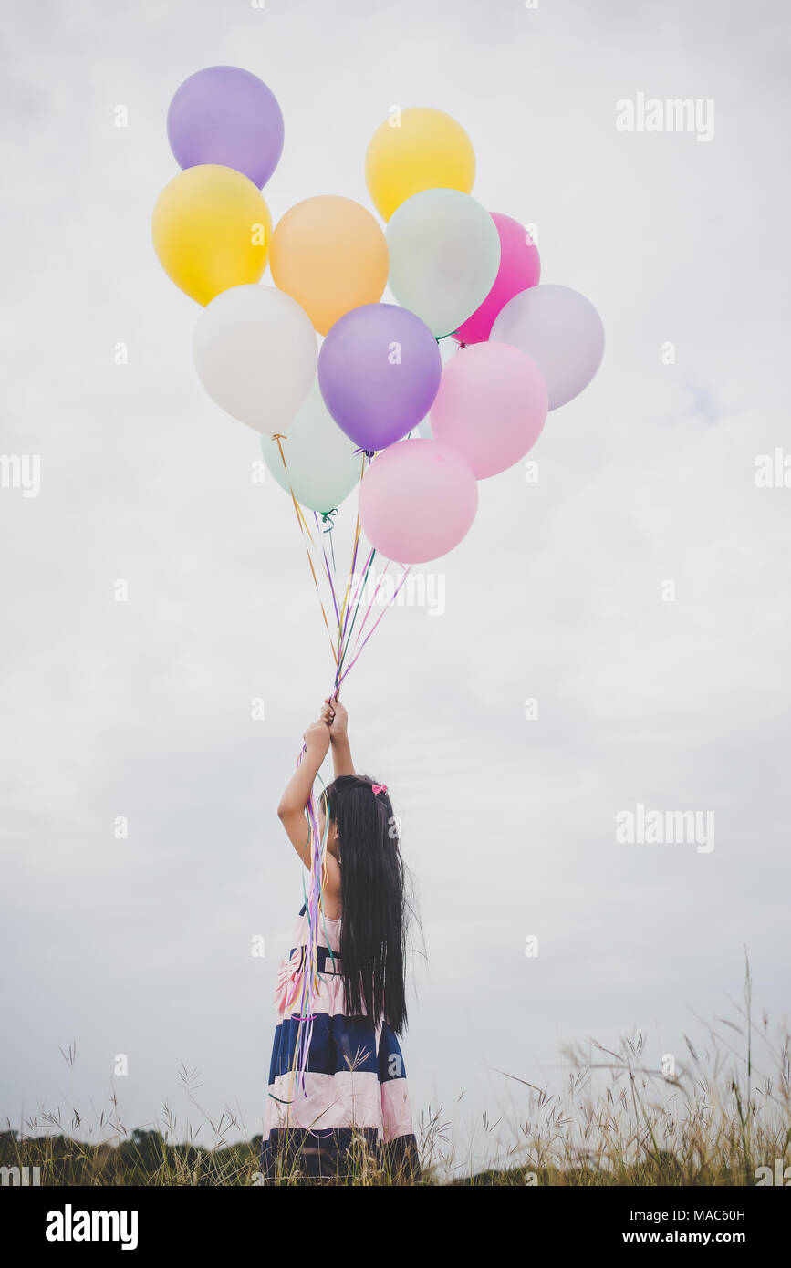 Little girl playing with balloons on meadows field Stock Photo - Alamy