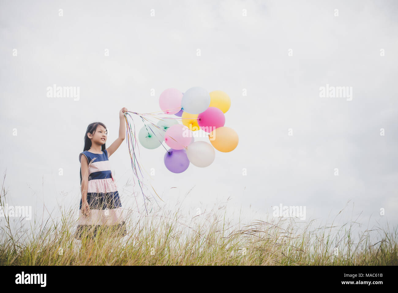 Little girl playing with balloons on meadows field Stock Photo - Alamy