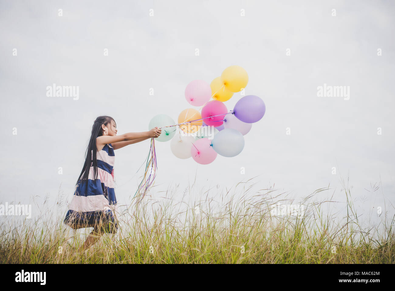 Little girl playing with balloons on meadows field Stock Photo - Alamy