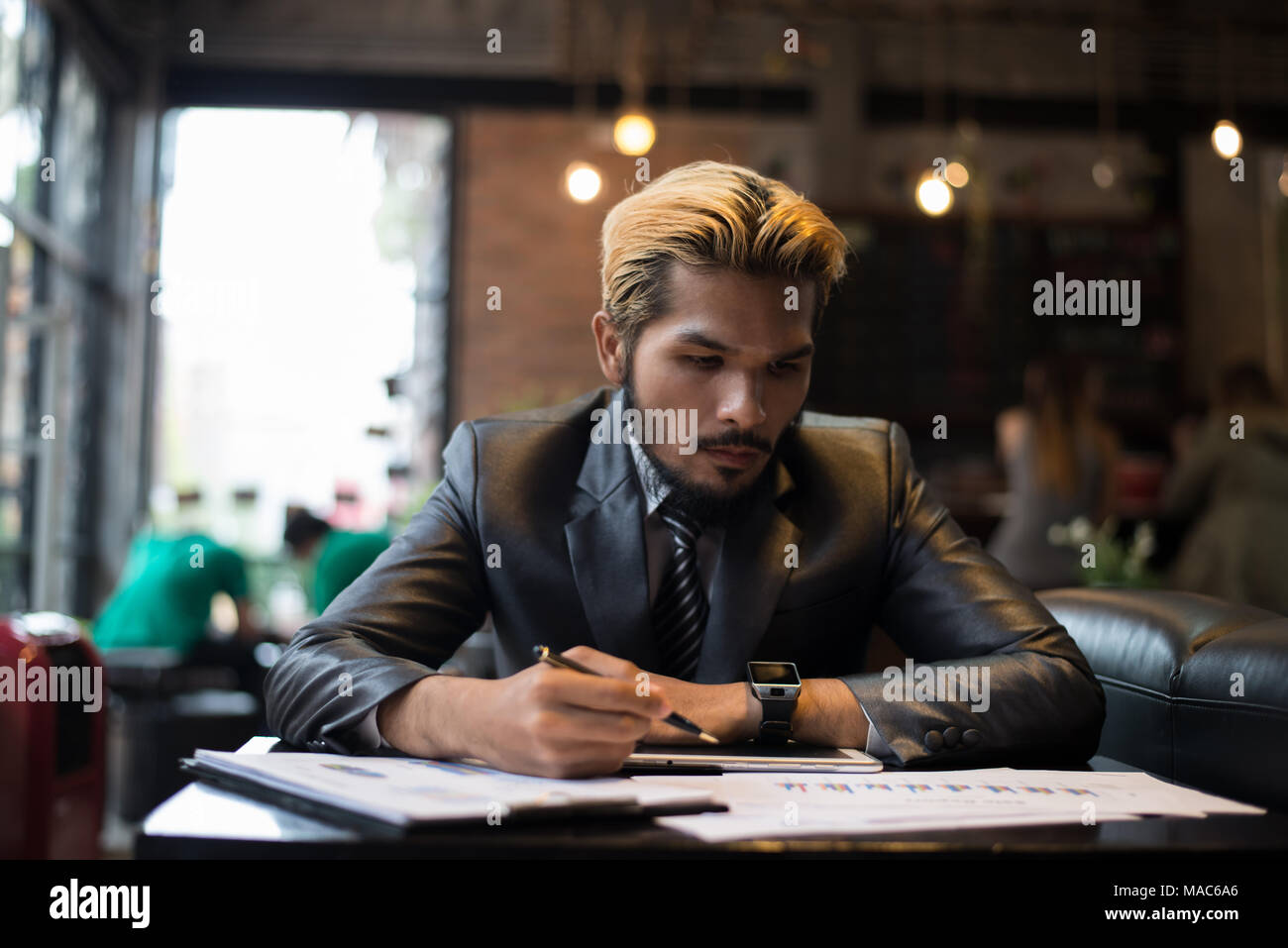 Handsome businessman writing on notebook with cup of coffee in restaurant. Stock Photo