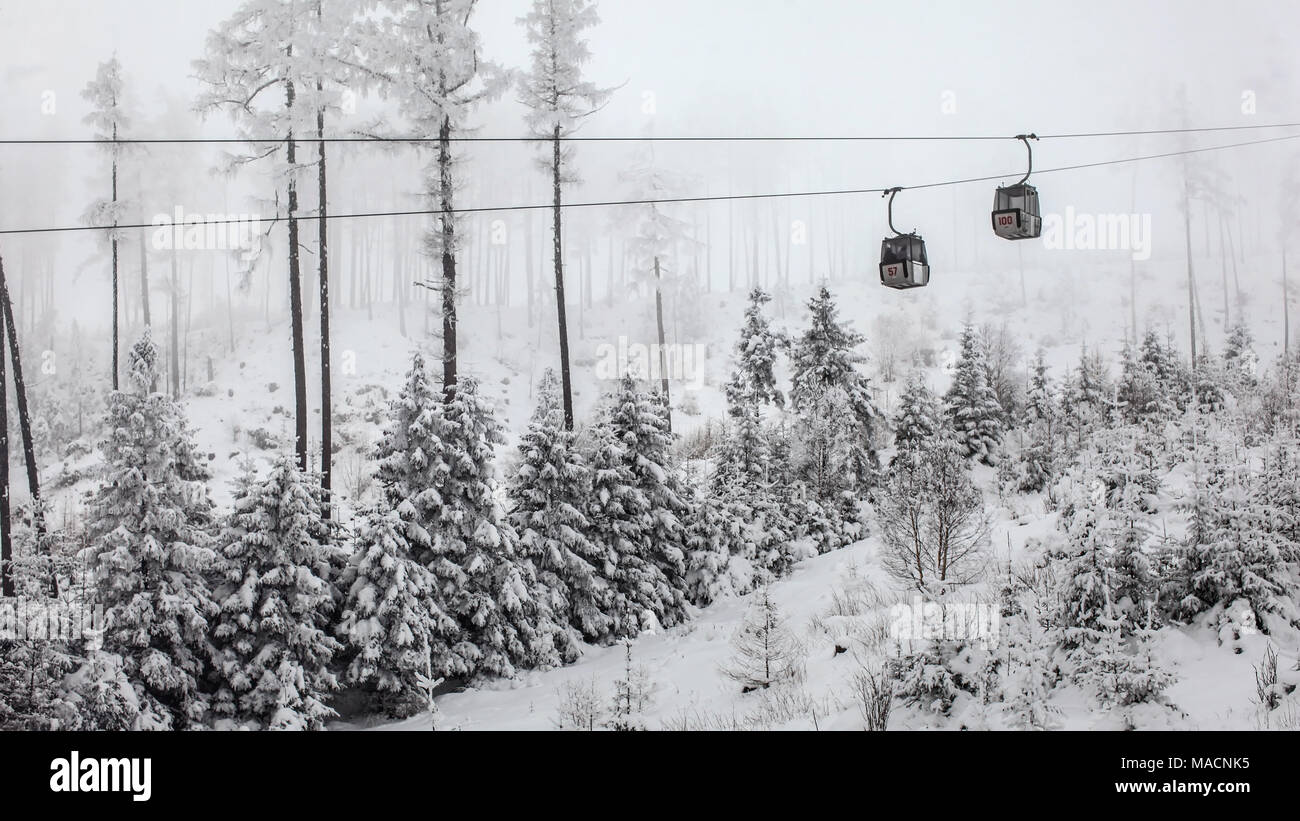 Two chairlift cabins passing each other on gray winter overcast day. Tatranska Lomnica ski resort, Slovakia Stock Photo