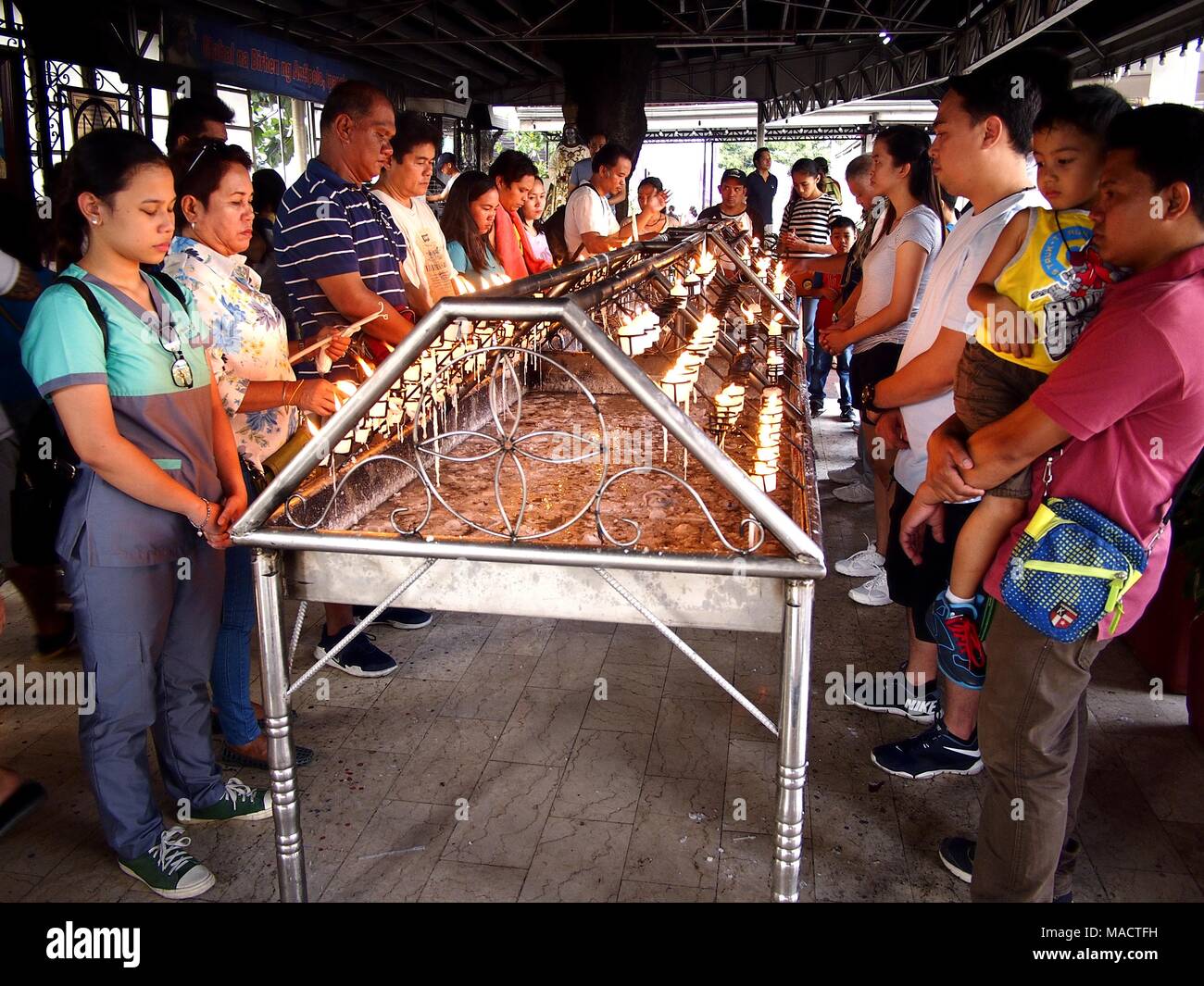 ANTIPOLO CITY, PHILIPPINES - MARCH 29, 2018: Catholic devotees pray and light prayer candles in Antipolo Cathedral or Our Lady of Peace and Safe Voyag Stock Photo