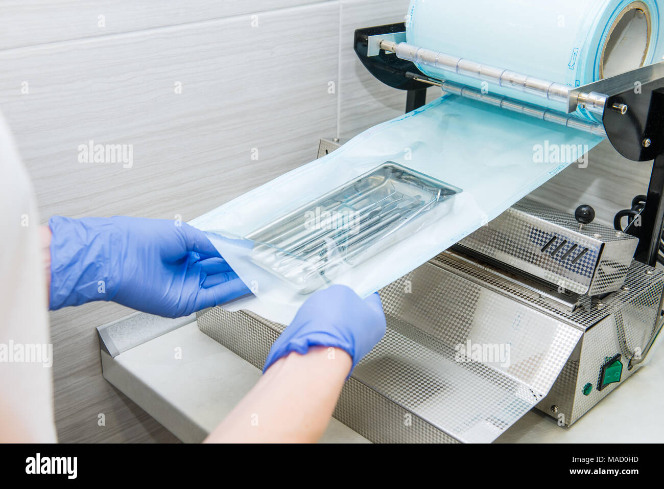 Close up dentist's assistant hands in gloves packing dental instrument