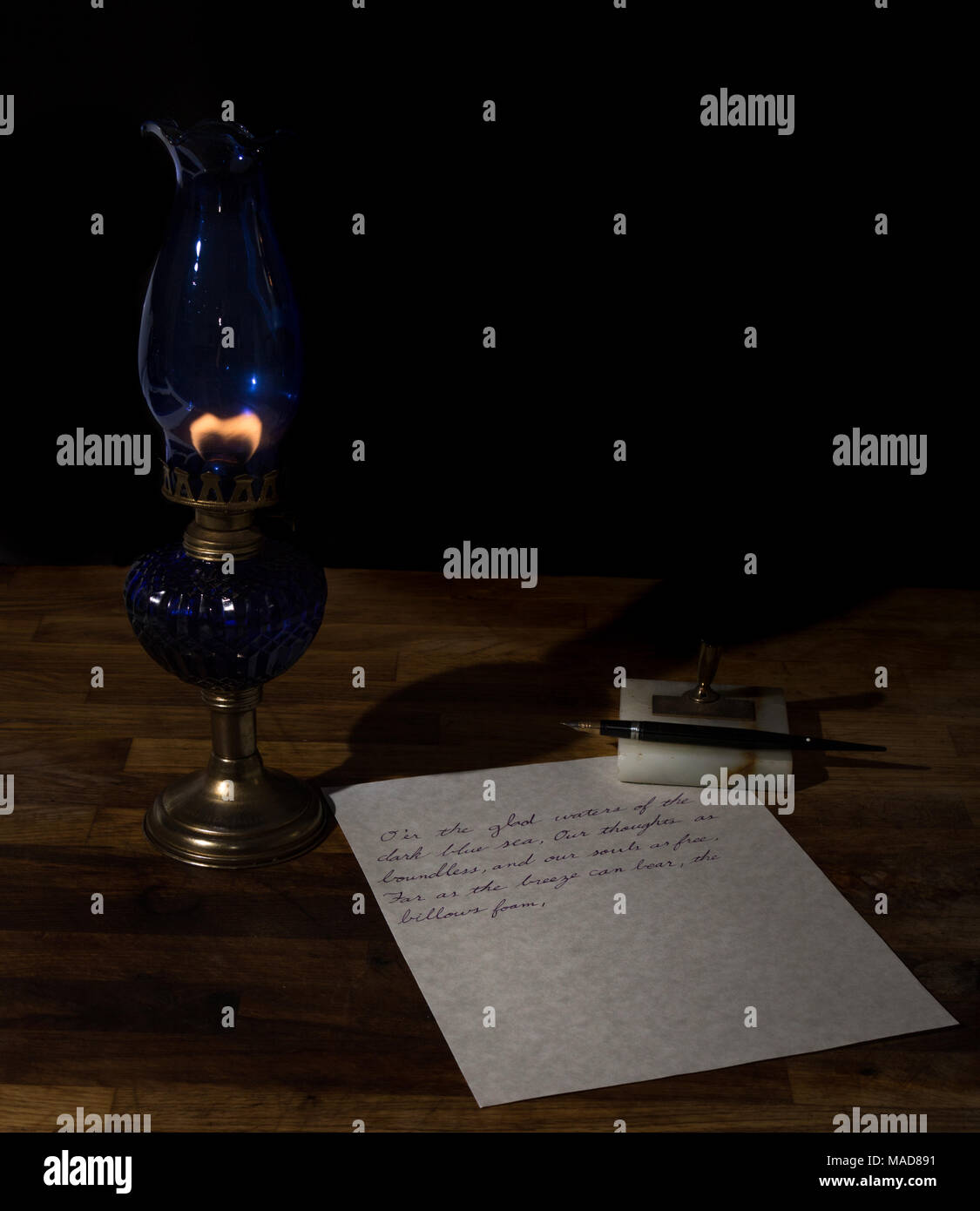 writing in a dimly lit room by an oil lamp Stock Photo
