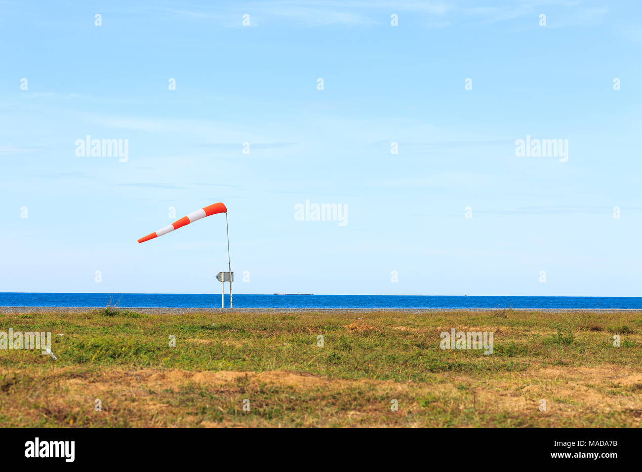 a wind force (windsock) against the dark sea and blue sky Stock Photo