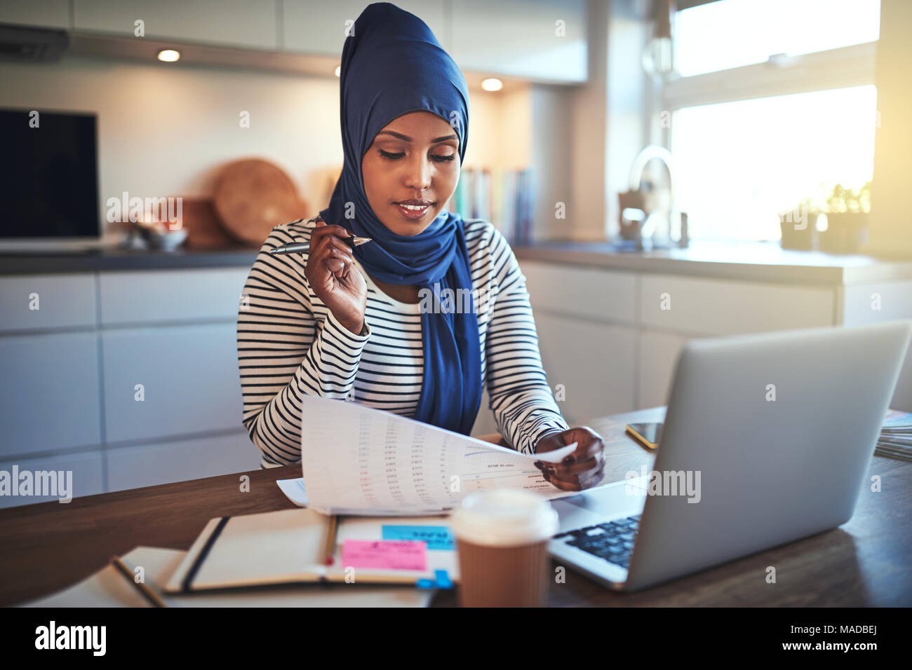 Young Arabic female entrepreneur wearing a hijab sitting at a table in ...