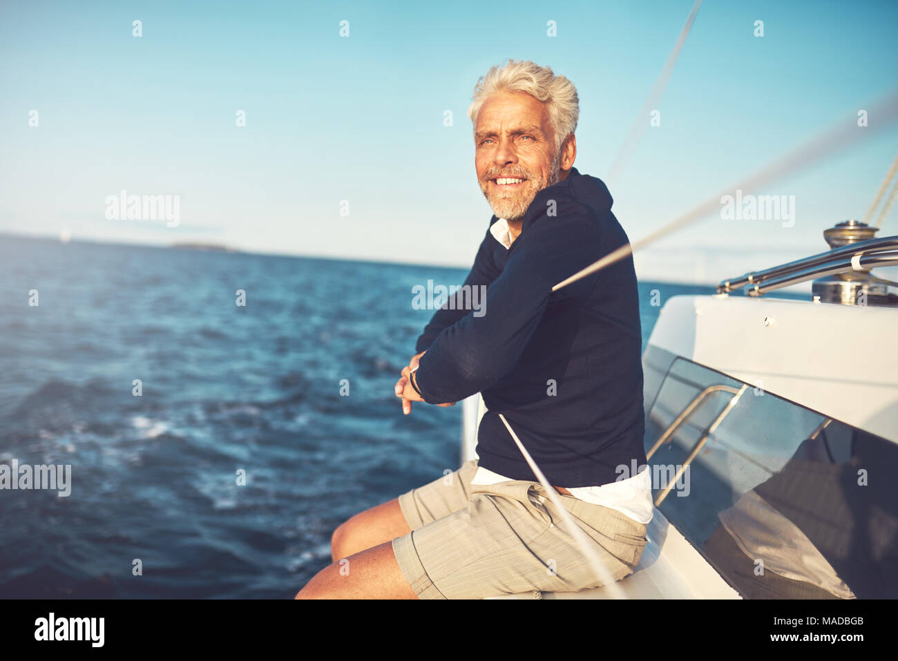 Smiling mature man enjoying the view from the deck of his boat while ...