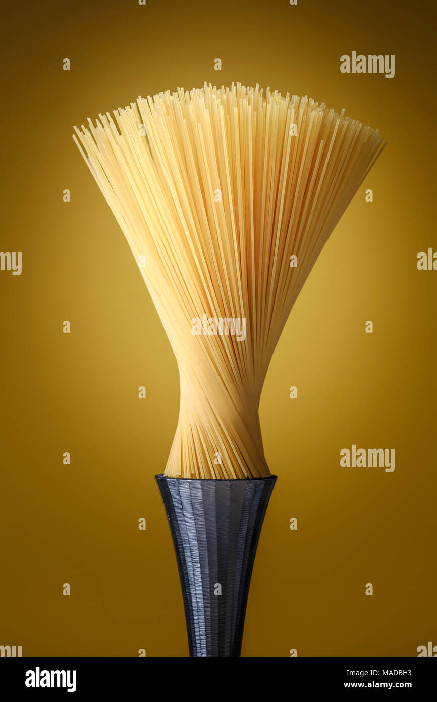 spaghetti pasta as a modern design artwork on a steel pedestal and resembling a brush, food concept. Stock Photo