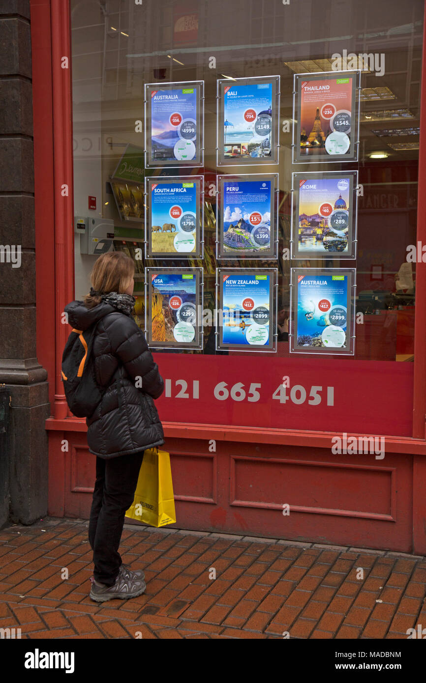 Young female looking at adverts in the window of the Flight Centre store in Birmingham, England. Stock Photo
