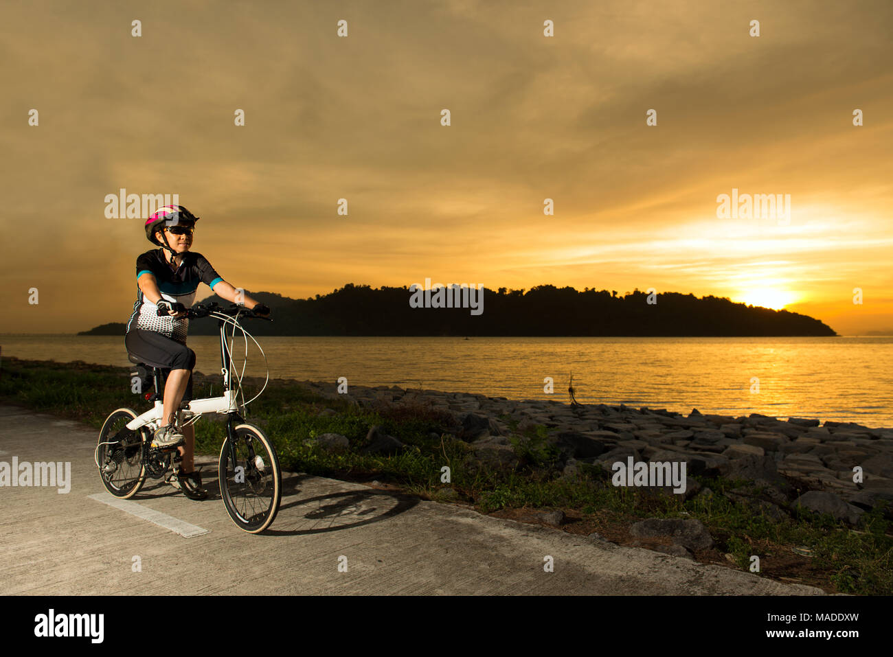 Senior woman cyclist at sunset Stock Photo