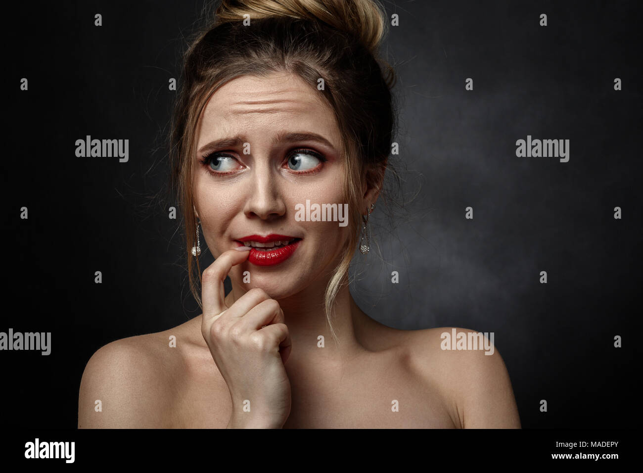 stressed fun girl with finger on mouth on black background looking aside Stock Photo