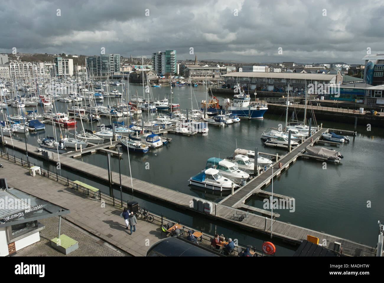 Yachting Marina in the historic Barbican Plymouth UK. Yachts lined up on jetties with fish market in the background. Sunny/ Cloudy skies. Stock Photo
