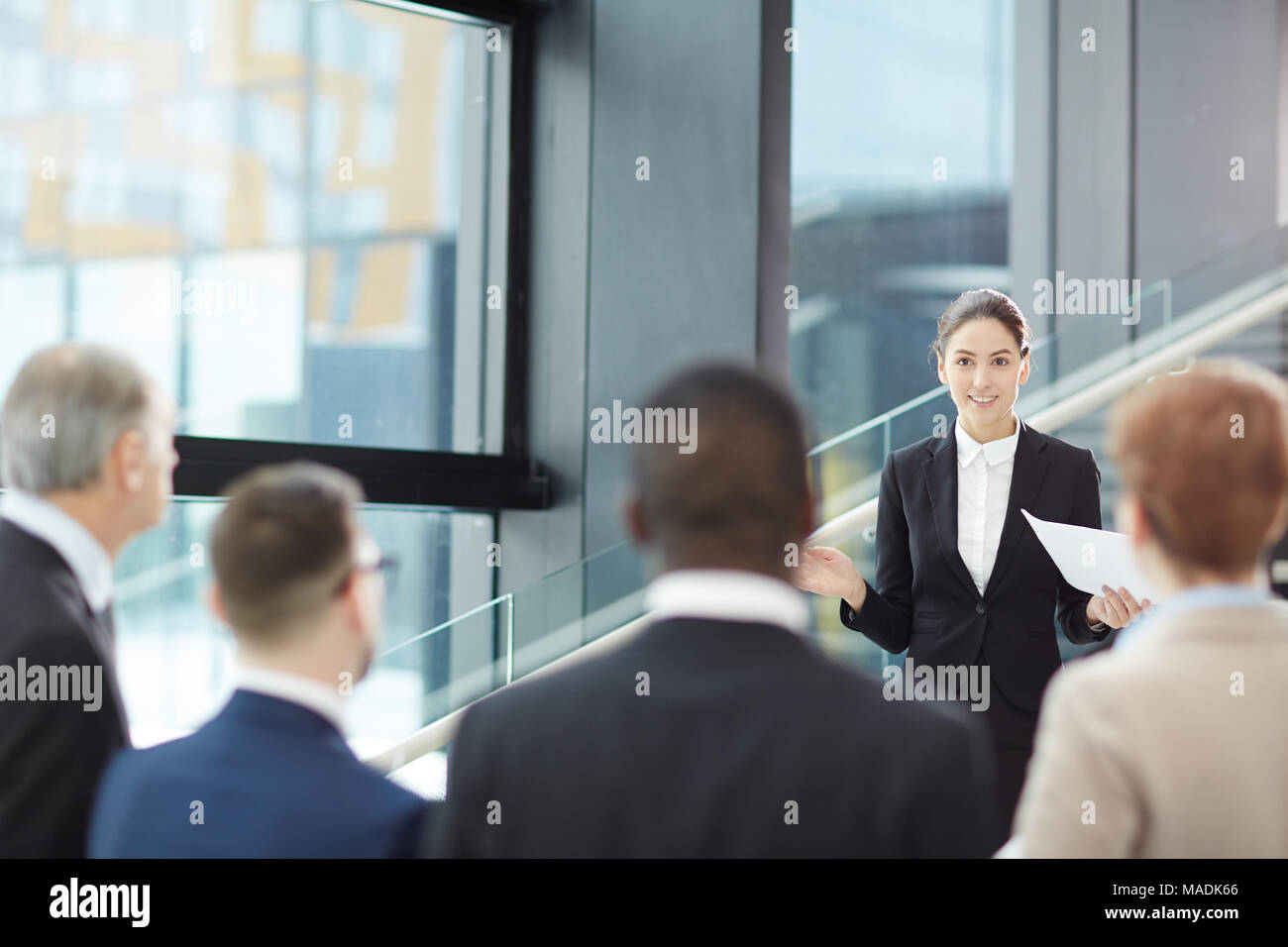 Young elegant businesswoman making report for her colleagues during or before conference Stock Photo