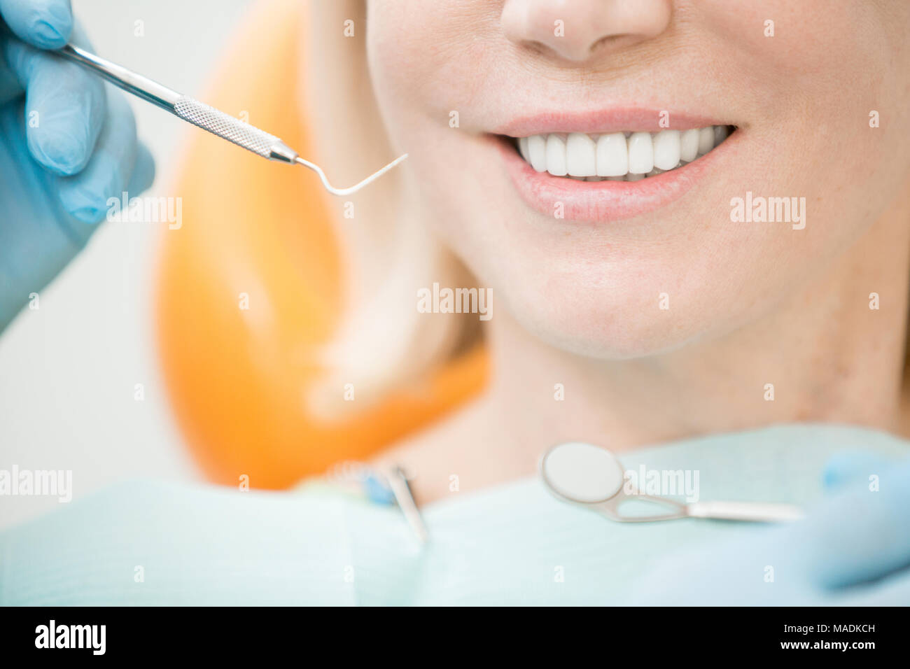 Dental hook and mirror held by dentist and toothy smile of healthy