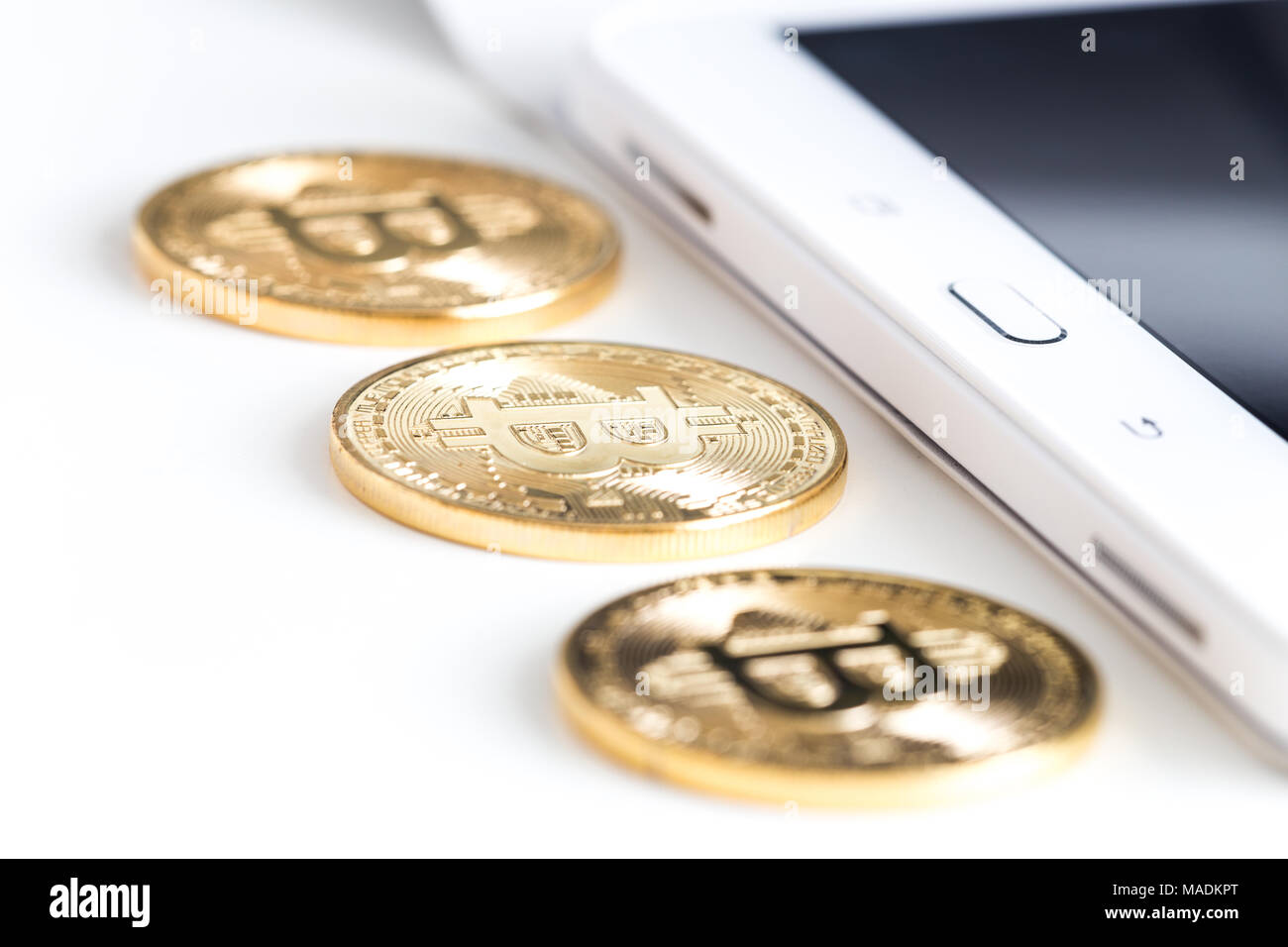 Bitcoins on a white table next to the tablet Stock Photo