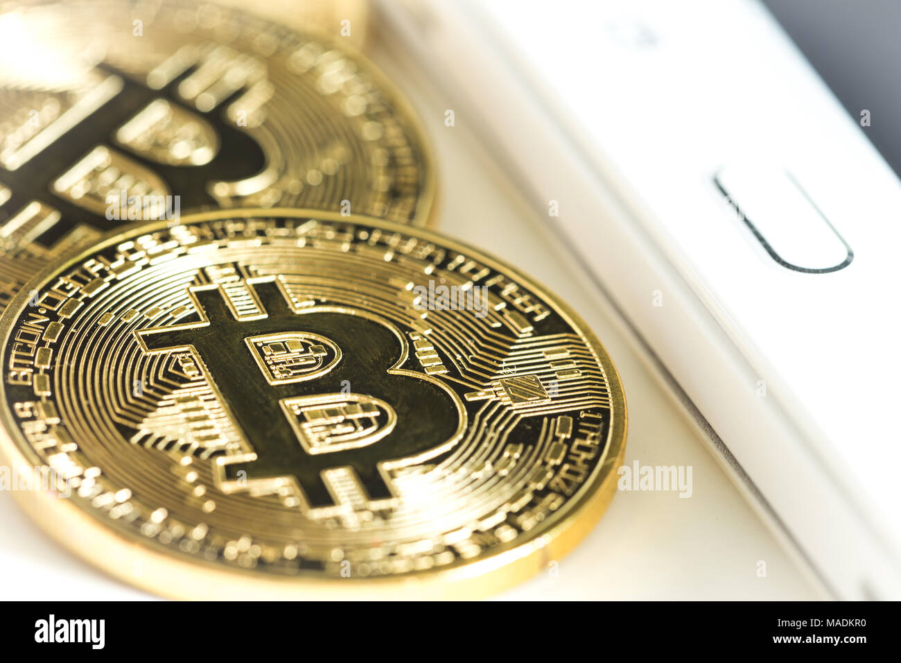 Bitcoins on a white table next to the tablet Stock Photo