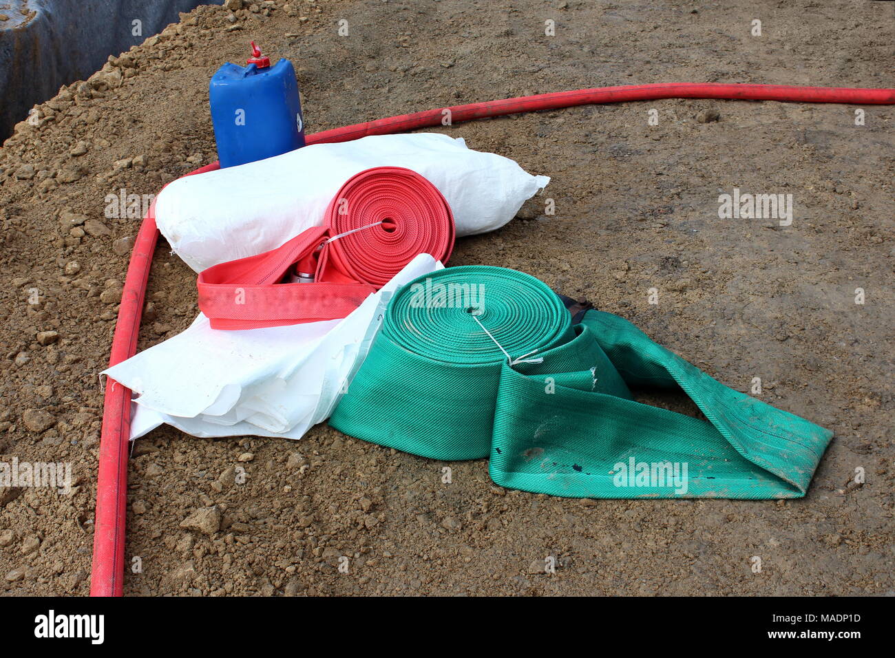 Water pump hoses tied in spiral, bags ready for filling with sand for