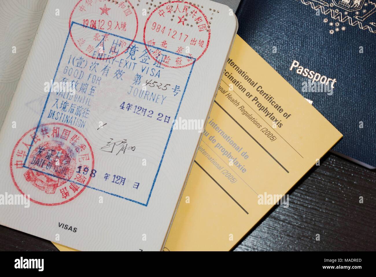 Blue Passport and open passport with asian visa stamps and an international vaccination certificate Stock Photo