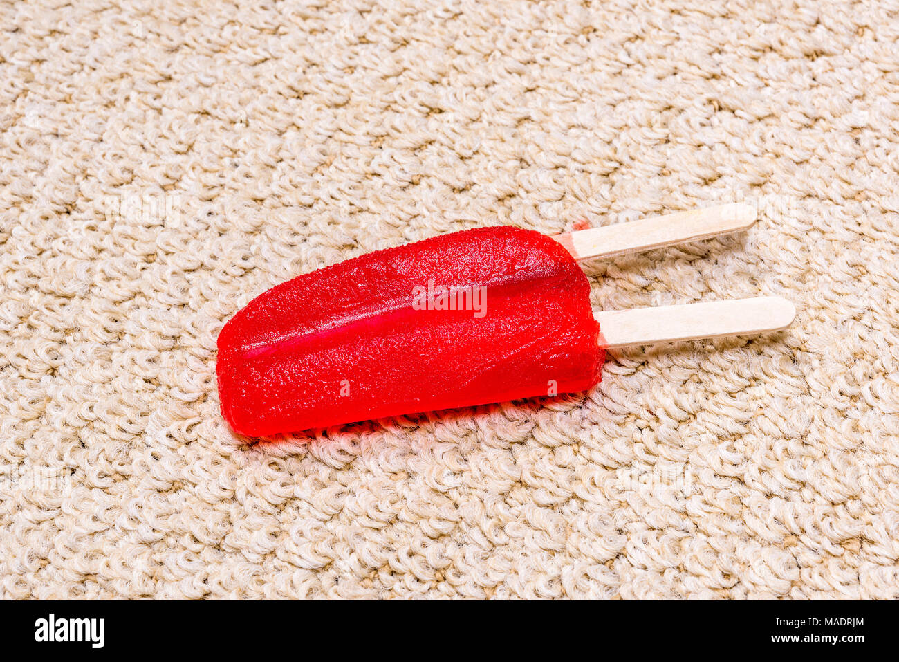 A time lapse of a melting popsicle on white carpet shows the icy treat melt into a sticky juice and absorb right into the carpet. Stock Photo