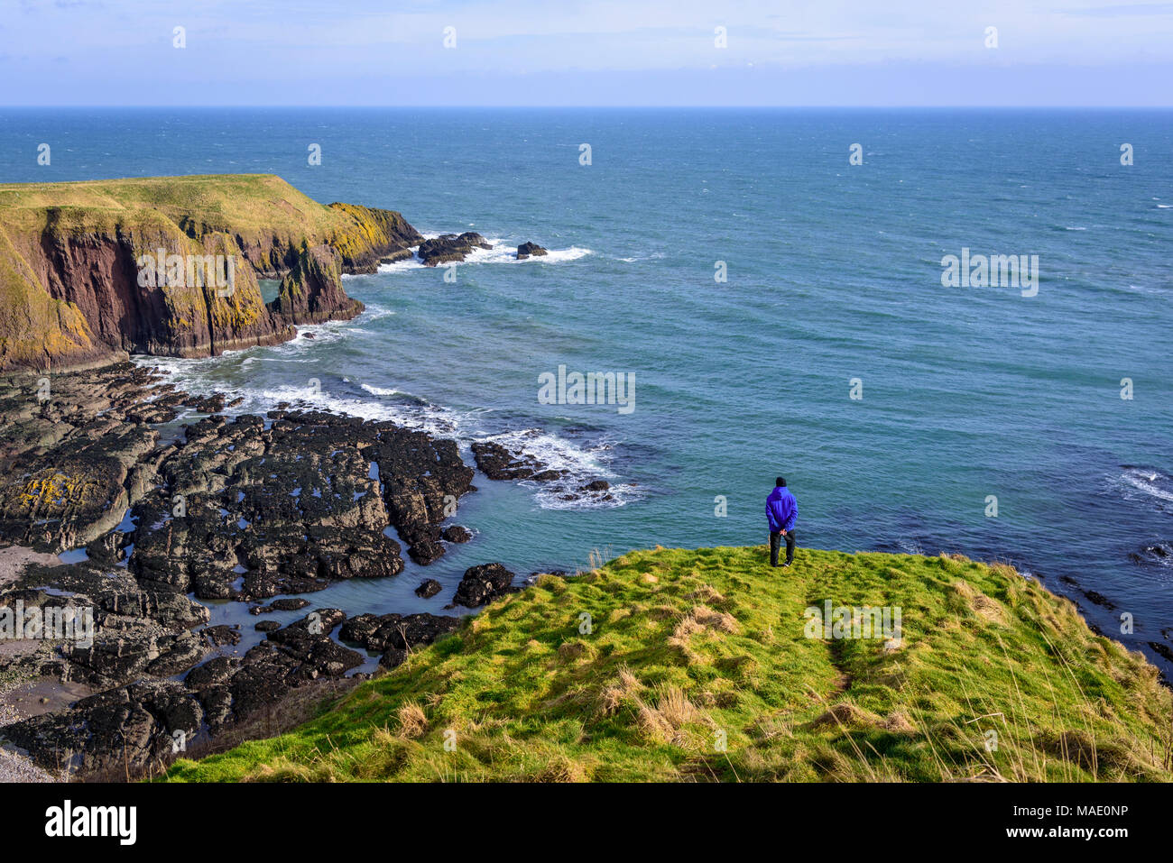 A lone firure looks out to sea from clifftop. Stock Photo