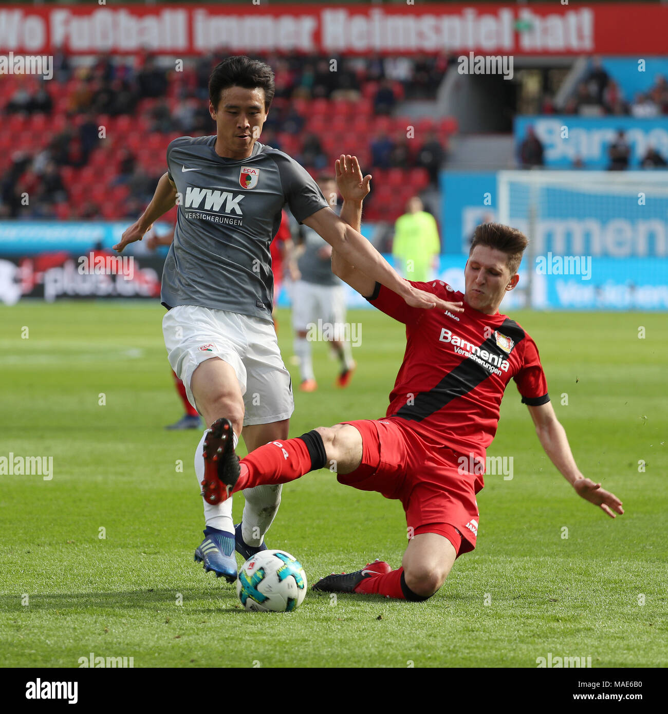 Leverkusen. 31st Mar, 2018. Retsos (R) of Bayer 04 Leverkusen vies with Koo Ja Cheol of FC Augsburg during the Bundesliga match between Bayer 04 Leverkusen and FC Augsburg at BayArena on March 31, 2018 in Leverkusen, Germany. The match ended with a 0-0 draw. Credit: Ulrich Hufnagel/Xinhua/Alamy Live News Stock Photo
