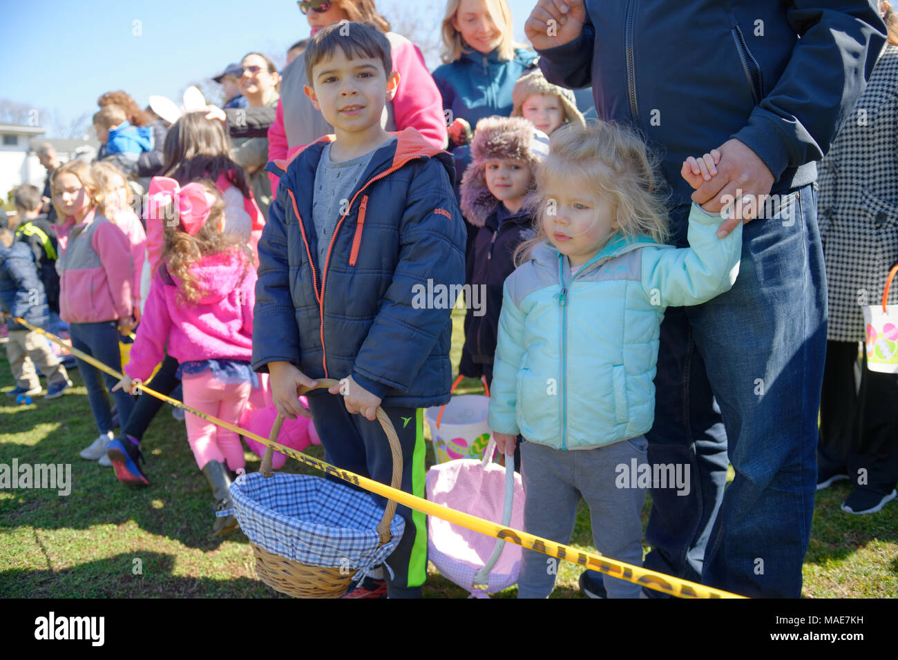 North Merrick, New York, USA. March 31, 2018. Young girls and boys eagerly wait behind yellow tape for start of traditional Easter Egg Hunt at the Annual Eggstravaganza, held at Fraser Park and hosted by North and Central Merrick Civic Association (NCMCA). Credit: Ann E Parry/Alamy Live News Stock Photo