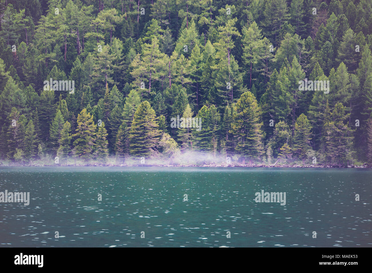 View on crystal clear lake with mist and reflection on the water. Stock Photo