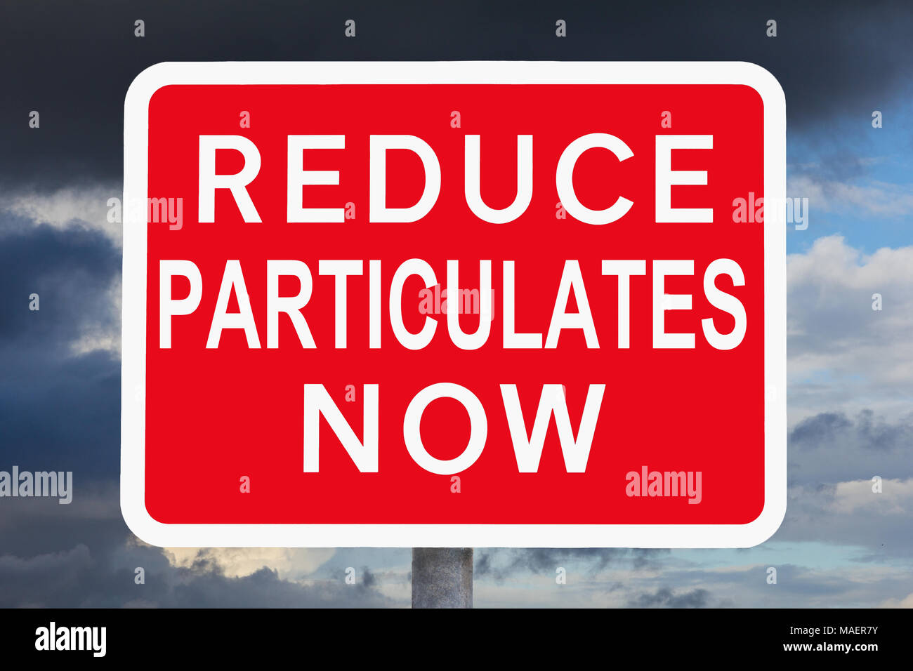 Red and white warning sign REDUCE PARTICULATES NOW in front of a sky with very dark clouds, variation of a british traffic sign Stock Photo