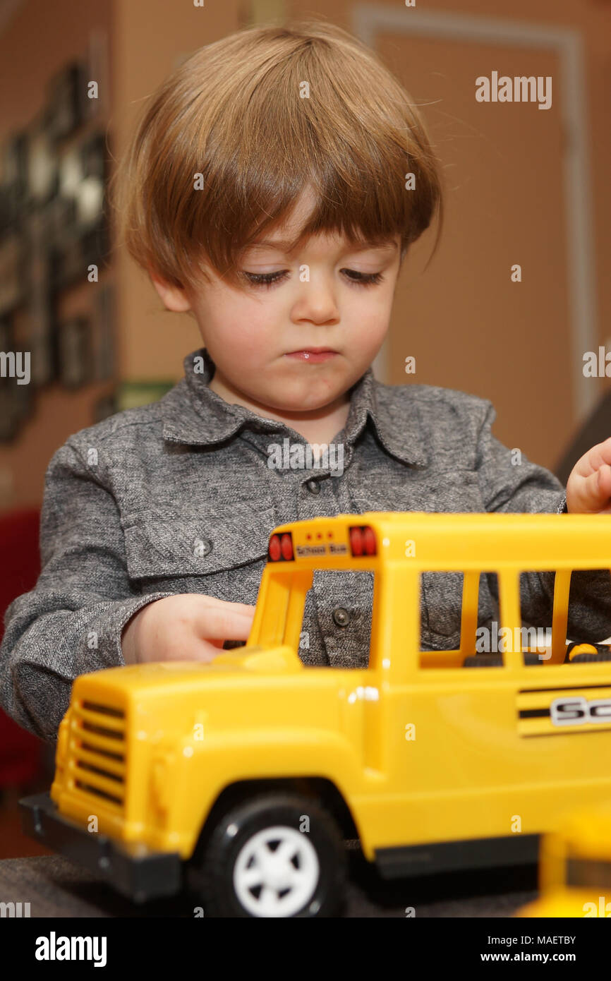 Montreal,Canada,31,March,2018.Young 3-year old boy playing indoors with a toy school bus.Credit:Mario Beauregard/Alamy Live News Stock Photo