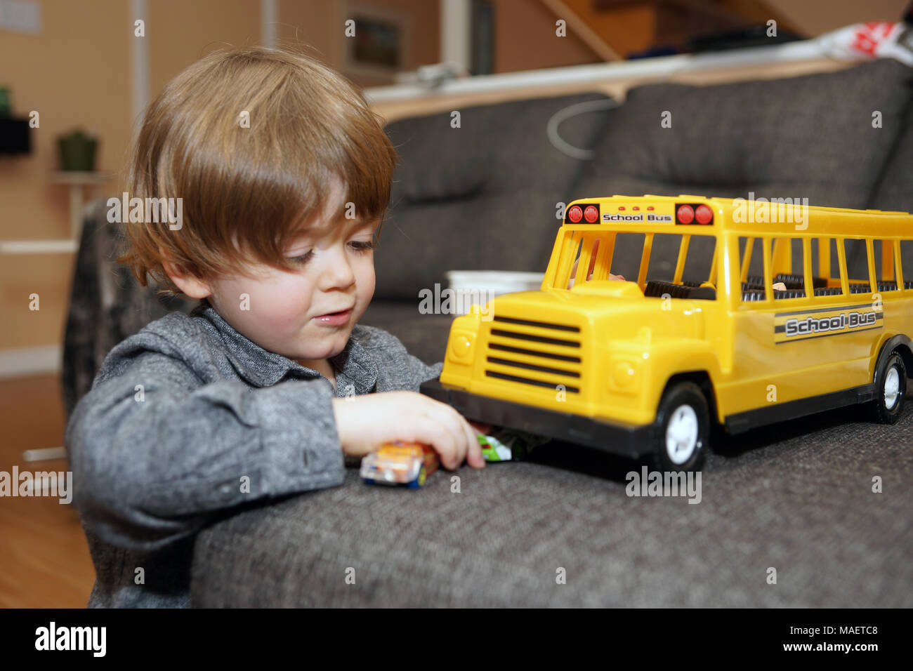 Montreal,Canada,31,March,2018.Young 3-year old boy playing indoors with a toy school bus.Credit:Mario Beauregard/Alamy Live News Stock Photo