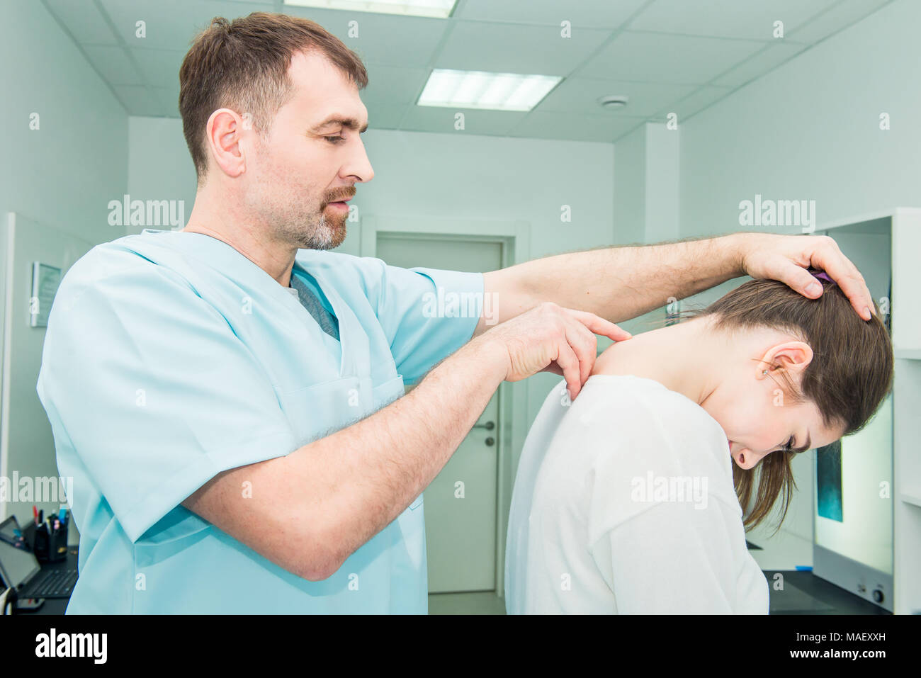 Male neurologist doctor examines cervical vertebrae of female patient spinal column in medical