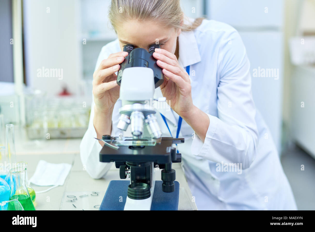 Busy female biologist using microscope in lab Stock Photo