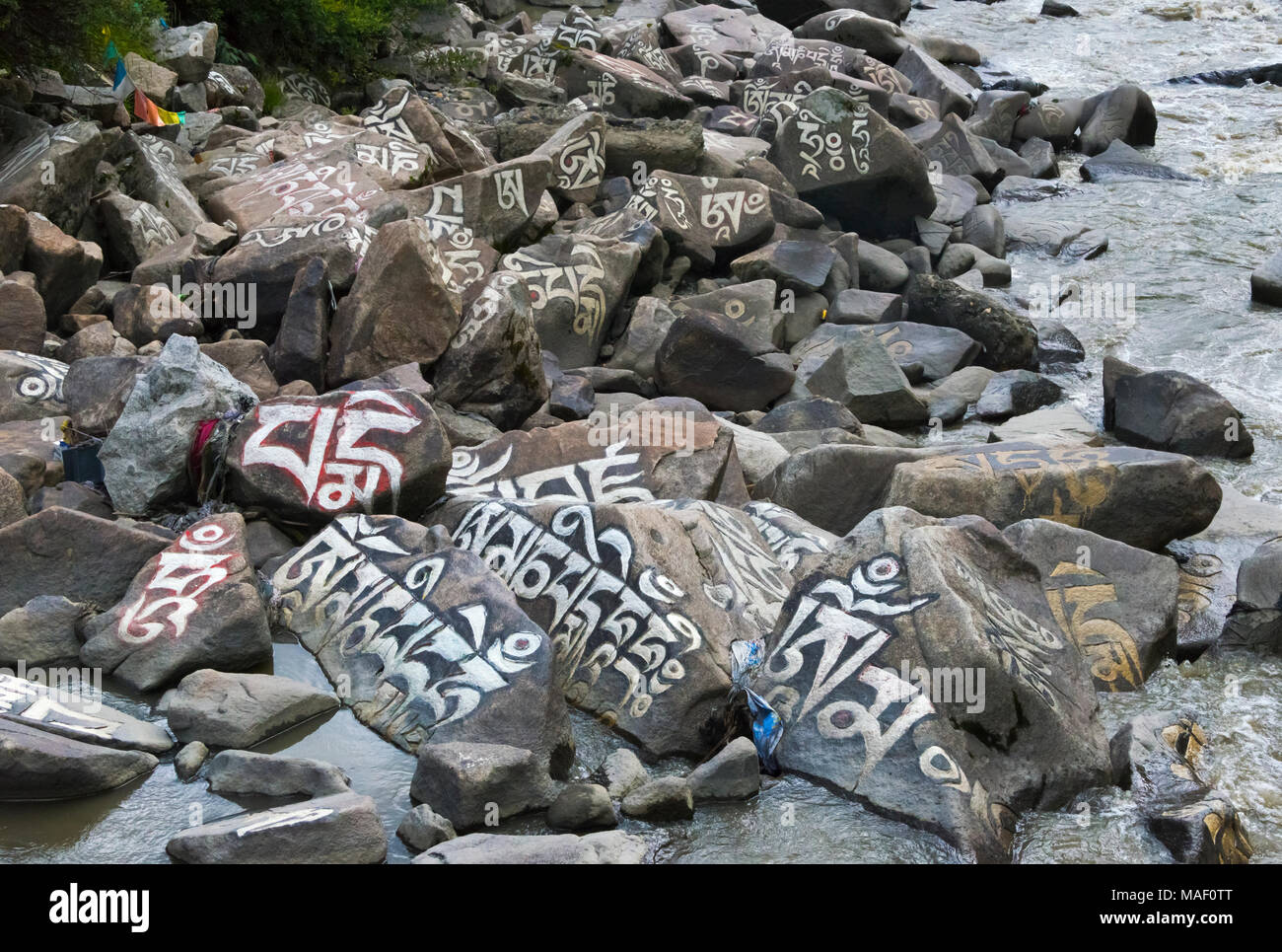 Rocks painted with prayer words in the river, Tagong, western Sichuan ...