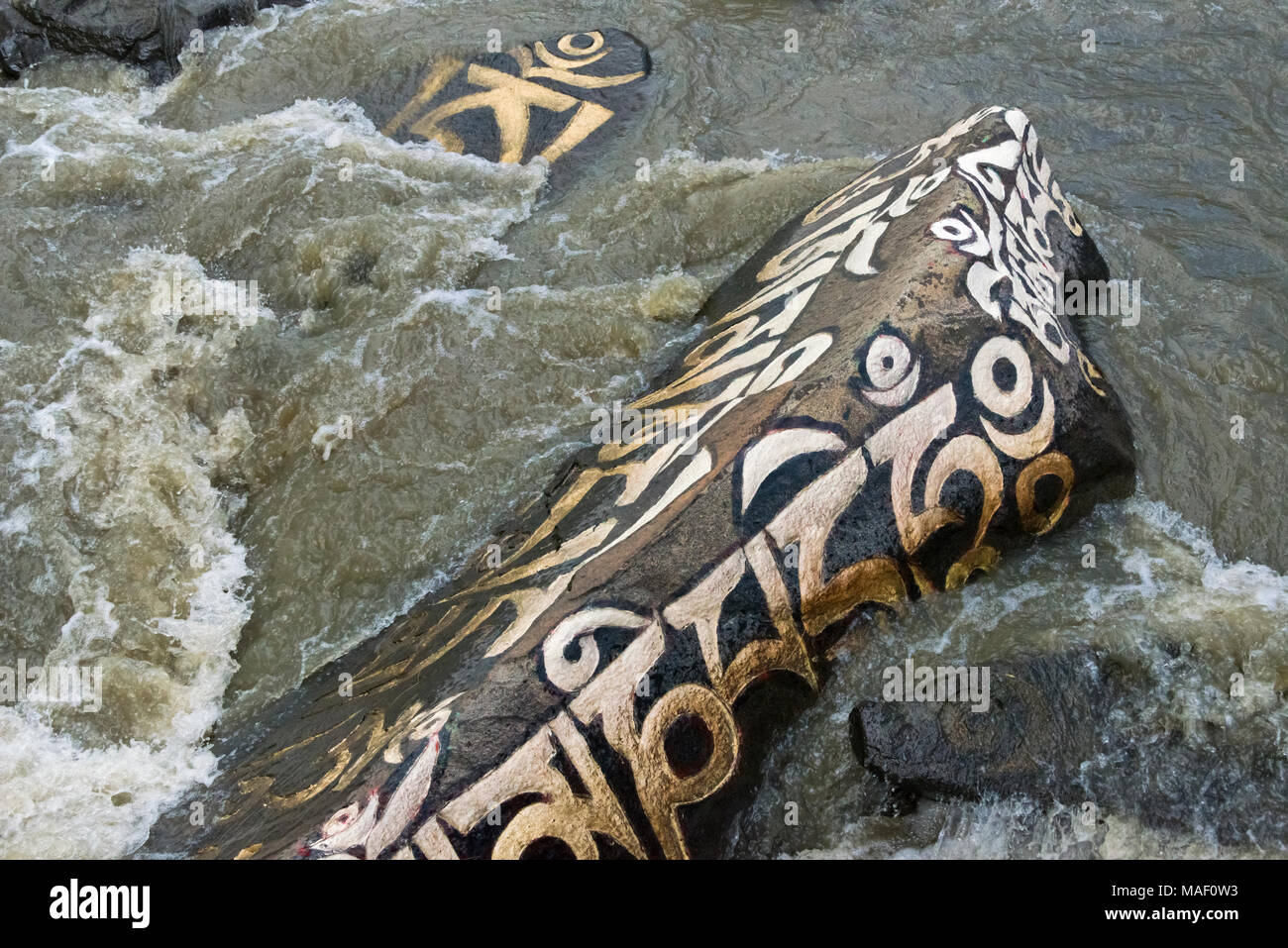 Rocks painted with prayer words in the river, Tagong, western Sichuan ...