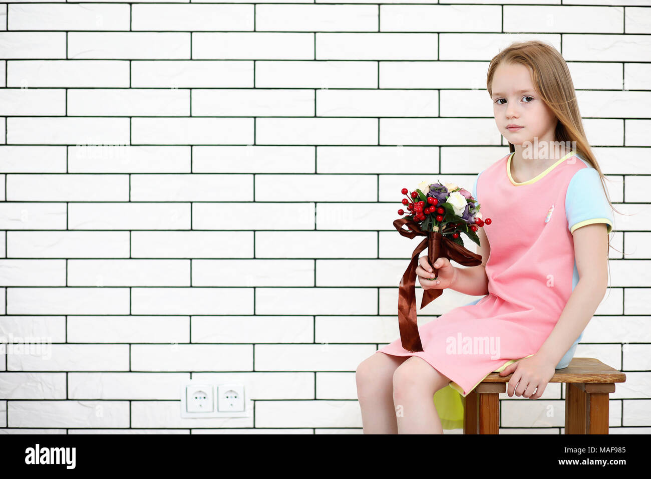 little girl is sitting on a chair and posing on the camera Stock Photo ...