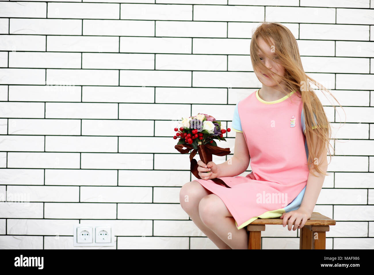 little girl is sitting on a chair and posing on the camera Stock Photo ...