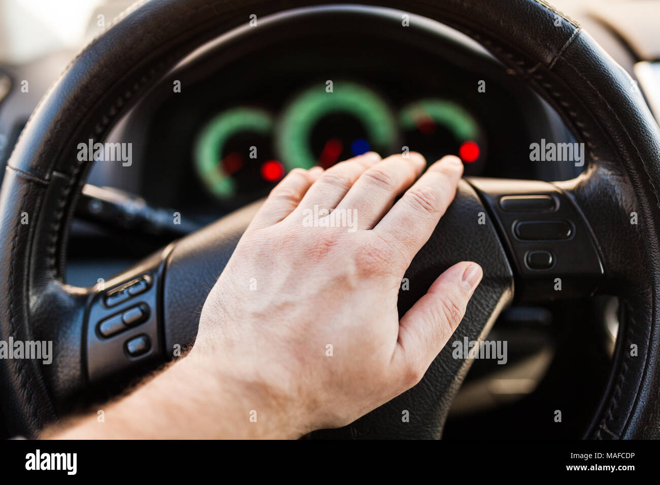 Close up shot of a man's hands holding a car's steering wheel and