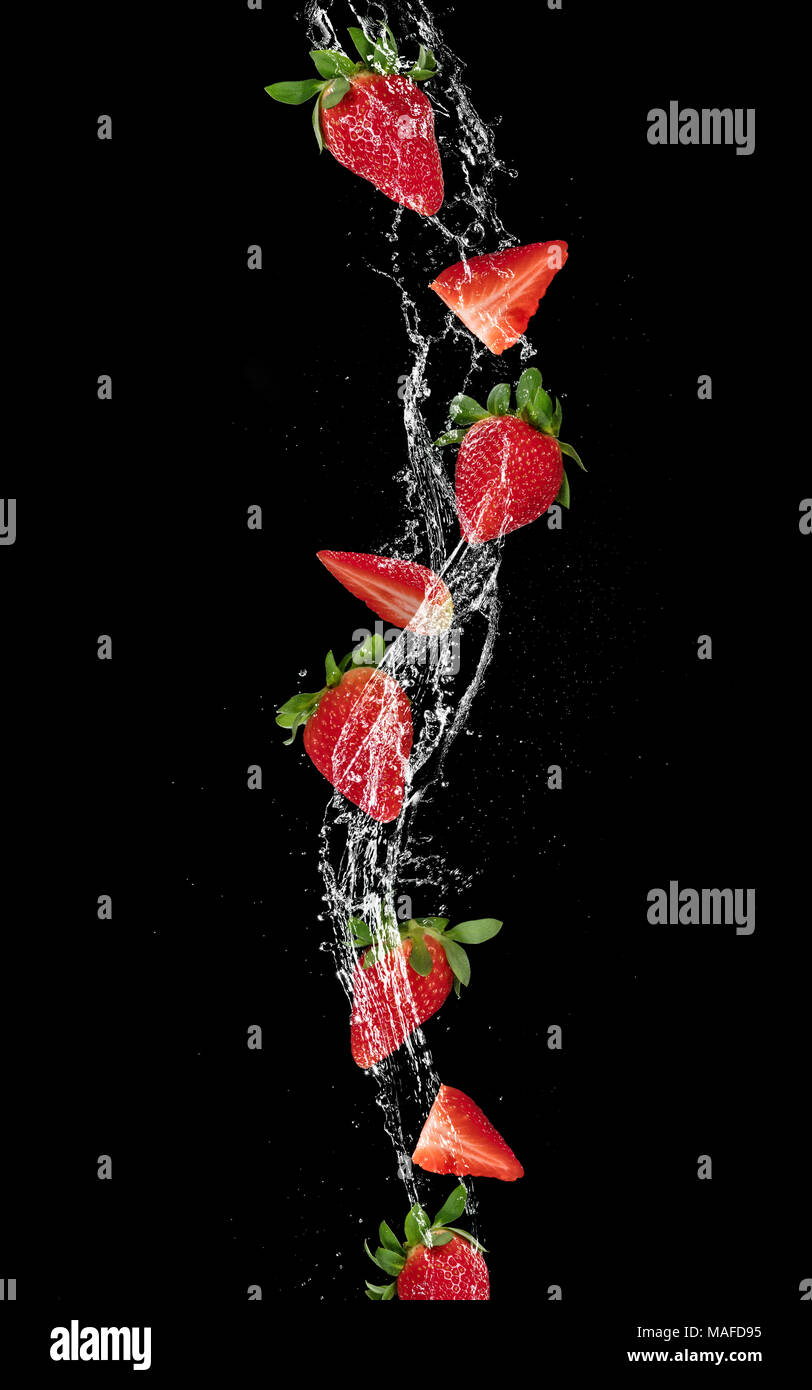 Pieces of strawberries and ice cubes falling in water splash, isolated ...