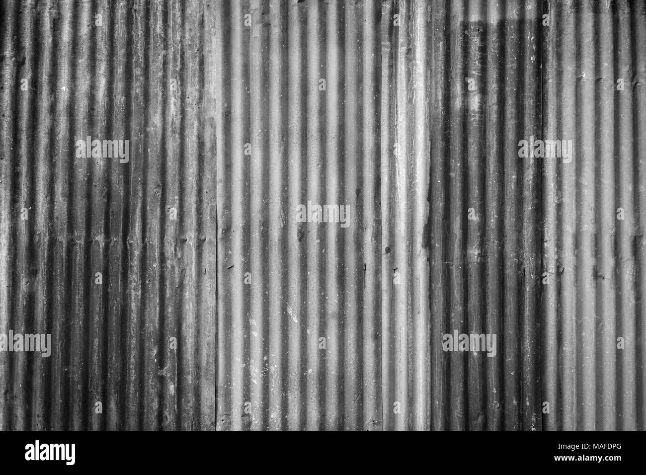 Rusty and corrugated iron metal construction site wall texture background with vignette in black and white. Stock Photo