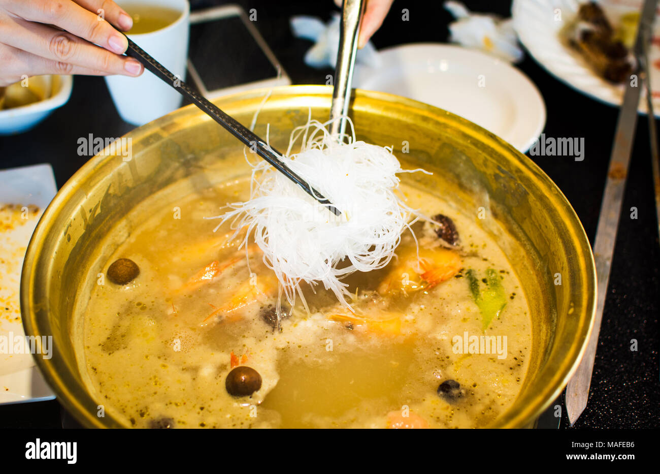 Chopsticks inserting glass noodle into boiling hotpot Stock Photo