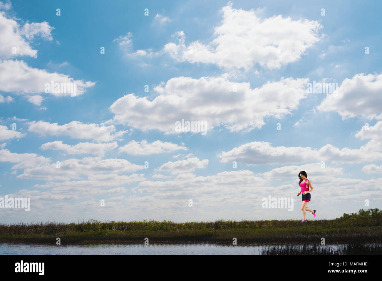 Running girl on a green field and bright sky Stock Photo